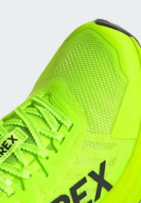 Scarpa sportiva di un vivace verde neon con tomaia in rete testurizzata, punta rinforzata e marchio nero a contrasto sul lato.