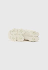 Hvid sportsko sål med tekstureret gummi, der har diamantmønstre og afrundede kanter, mærket med "new balance."