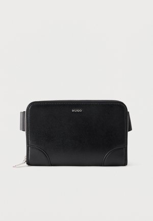 Clutch Hugo de cuero negro texturizado con cremallera, costuras en las esquinas y correa lateral sobre fondo blanco.