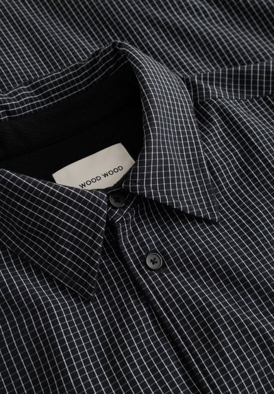 Kortærmet skjorte i mørk marineblå stof med hvidt ternet mønster, klassisk krave og to sorte knapper foran. Label synlig.