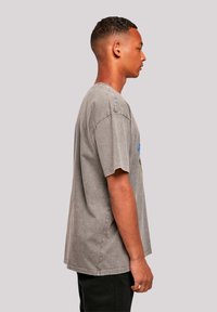 Gray cotton t-shirt with a relaxed fit, featuring short sleeves and slight distressing, viewed from the side.