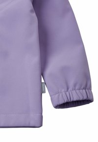 Veste lilas clair avec une texture lisse et mate, des poignets élastiques et une petite étiquette de logo sur la manche.