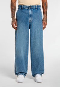 Light blue oversized denim jeans with a high waist and wide legs, featuring a traditional button closure and side pockets.