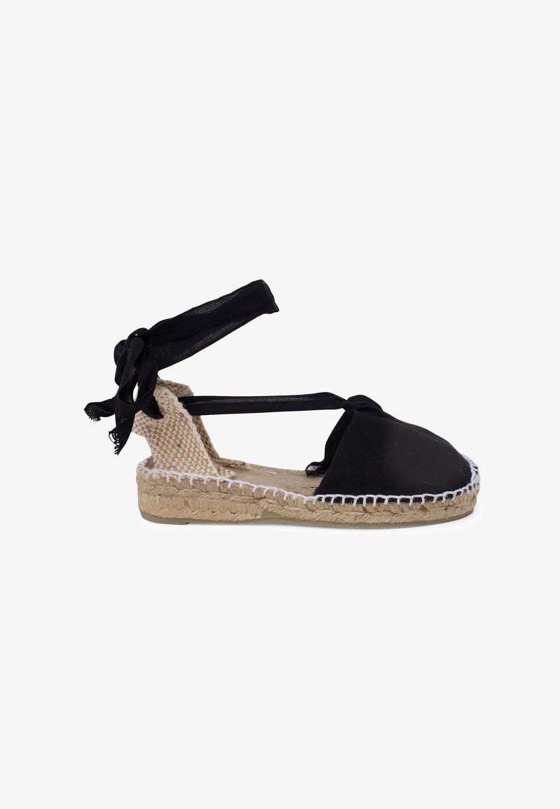 Musthave musta kangakang espadrill, millel on pahkluudele seotud paelad, jute kate tallal, valged õmblused ja ümar nina. Üks lihtne disain, mis sobib soojade ilmadega.
