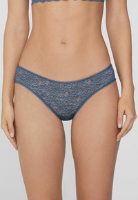 Koronkowe bielizna bikini w ciemnoniebieskim kolorze, zdobiona kwiatowymi wzorami, z falbaniastymi brzegami i miękką teksturą. Średni stan i dopasowany krój.