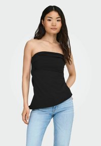 Mustmustärgne top, millel on sobiv kehaosa, pehme tekstuur ja kerge laienemine hemil, kombineeritud helesiniste teksadega.