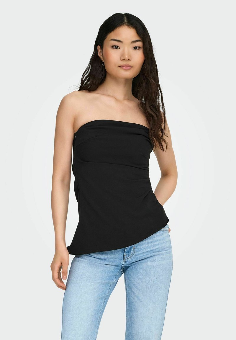 Mustmustärgne top, millel on sobiv kehaosa, pehme tekstuur ja kerge laienemine hemil, kombineeritud helesiniste teksadega.