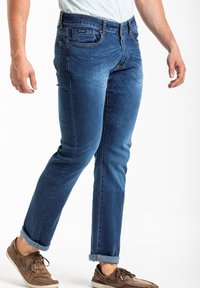 Jean en denim bleu foncé avec une coupe droite, un design à cinq poches et des poignets retroussés. Présente une légère décoloration et des détails de couture.