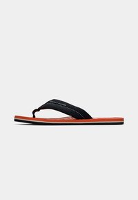 Red sole flip-flop sandal with black fabric strap featuring white stitching and Tommy Hilfiger logo on a white background.