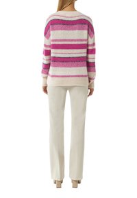 Gestreifter Pullover mit rosa, weißen und grauen Garnen, mit einem lässigen Schnitt und gerippten Bündchen, kombiniert mit cremefarbenen langen Hosen und High Heels.
