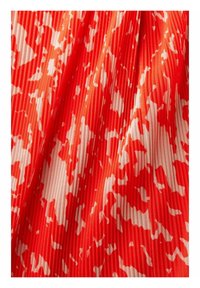 Tissu à motifs rouge et blanc avec une texture côtelée, présentant des formes abstraites dans un mélange de couleurs.