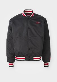 Black satin bomber jacket with striped red and white ribbed collar and cuffs. Features snap-button closure and side pockets. Logo on chest.