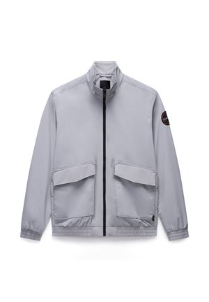 Lichtgrijze zip-up jas met hoge kraag, twee voorzakken, elastische manchetten en een logo patch op de linkermouw. Glad, lichtgewicht materiaal.