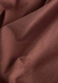 Bruin stof met een gladde textuur, voorzien van zachte plooien en een subtiele glans. De weving is strak, wat een gelijkmatig oppervlak creëert.