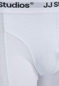 Weiße Baumwoll-Boxershorts mit einem weichen Bündchen und schwarzem "JJ Studios"-Logo. Glatte Textur mit verstärkten Nähdetails.