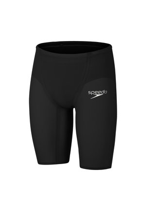 Bañadores tipo jammer negros hasta la rodilla con un logo blanco de Speedo en el muslo derecho, diseñados para natación de competición.