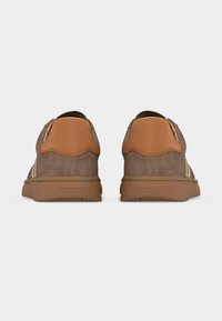 Ζευγάρι καφέ σουέντ αθλητικά παπούτσια με ταμπά δερμάτινα έμπλαστρα στη φτέρνα, σε λευκό φόντο, από πίσω.