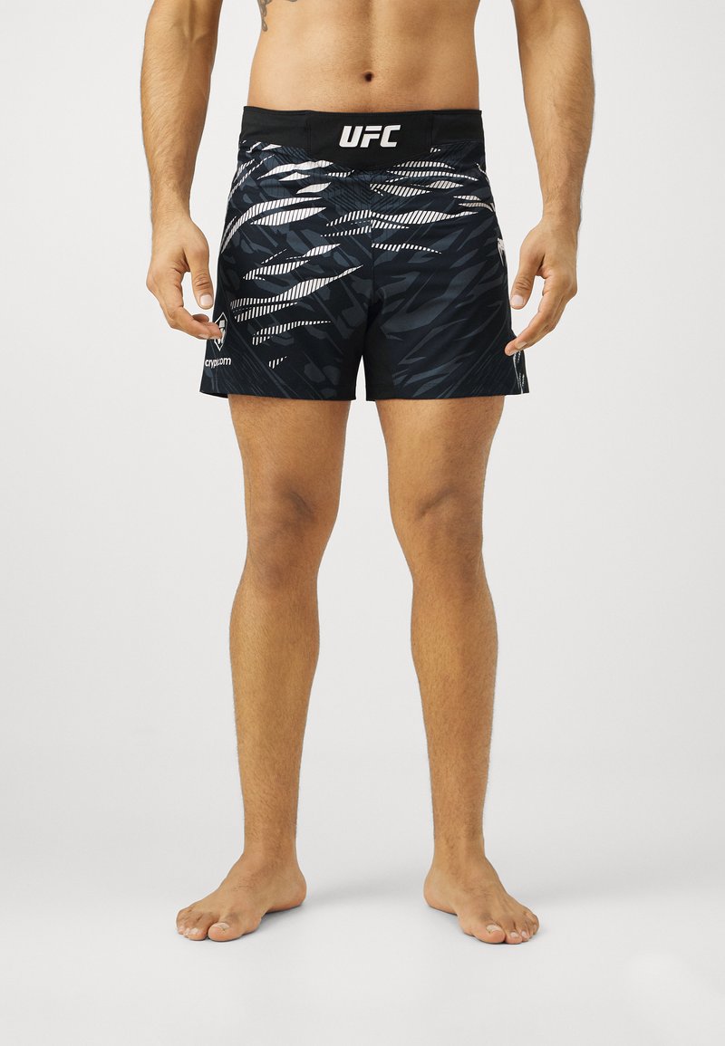 Bermudas negras con un dinámico patrón gráfico blanco, banda elástica en la cintura y logo de UFC. Tejido ligero con una textura suave, adecuado para deportes.