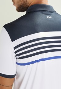 Pánská polo tričko s námořnickým límečkem, bílým tělem a horizontálními pruhy v námořnické a modré barvě. Měkká látka s obepínajícím střihem.