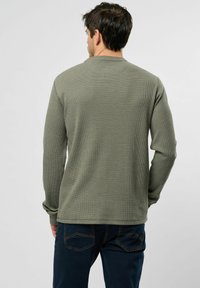 Groen lange mouwen wafelstrikshirt met ronde hals, zichtbare naden en een relaxed fit, gecombineerd met donkerblauwe jeans.
