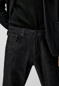 Svarta denimjeans med rak skärning, utrustade med knappstängning, fem fickor och subtila tvättm önster. Texturerad midja, slim fit.