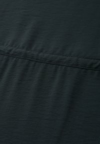 Tissu vert foncé avec un détail de couture horizontale et une légère texture, montrant des plis doux et des coutures au milieu.