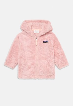 Veste à capuche rose en fausse fourrure avec une fermeture éclair à l'avant, deux poches latérales et une patch logo cousu sur la poitrine gauche. Texture douce et pelucheuse.