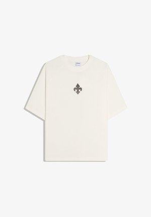 Valkoinen lyhythihainen T-paita, jossa pieni musta fleur-de-lis-symboli keskitettynä rintaan, yksivärinen tausta.