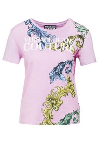 Růžové bavlněné tričko s dekorativním vícebarevným vzorem a výrazným bílým nápisem "VERSACE JEANS COUTURE" na přední straně.