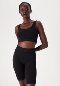 Zwart naadloos activewear set met een cropped tanktop en high-waisted shorts met een subtiel textuurpatroon en een gladde afwerking.