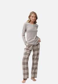 Top gris de manga larga con cuello redondo y detalles de botones, combinado con pantalones de pijama de cuadros beige que presentan acentos marrones y piernas anchas.