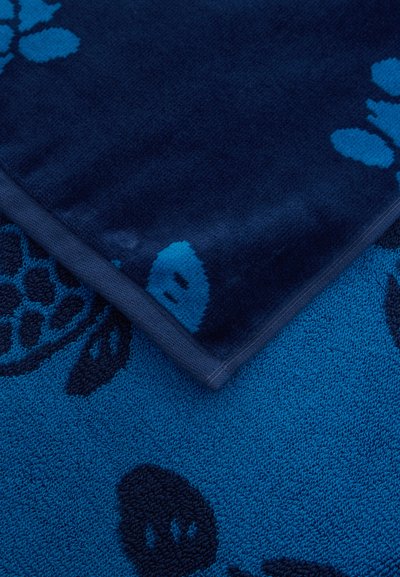 Σκούρα και ανοιχτά μπλε πετσέτες με υφή φύλλου και μούρου, μία πετσέτα διπλωμένη πάνω στην άλλη που δείχνει αντίθετα χρώματα και σχέδια.