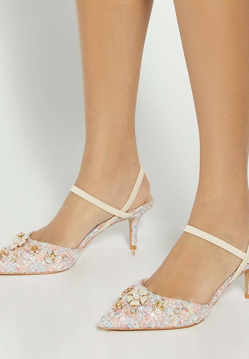 Pink textured slingback heels with a pointed toe, embellished with pearls and floral accents, and a slender stiletto heel.