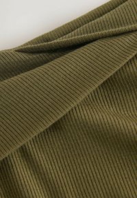 Olive green ribbed fabric with a smooth texture, featuring folds that create depth and subtle shadows. Close-up view emphasizes material detail.