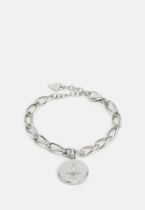 Bracelet chaîne en argent avec des maillons en forme de cœur et un pendentif rond gravé d'un motif rayons de soleil et petits cristaux, de la marque Guess.