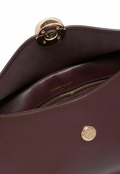 Interno di una borsa in pelle color bordeaux con una cerniera dorata e una placca con logo. Texture liscia e design strutturato, che mette in evidenza la qualità della lavorazione.