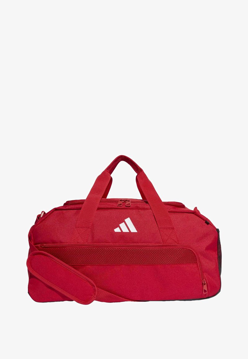 Bolsa de viaje roja con dos asas y correa de hombro desmontable. Presenta un panel de malla lateral y un logo blanco en la parte frontal. Material duradero.