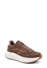 Zapatilla de ante marrón con acentos de malla, cordones tonales, collar acolchado y una entresuela blanca gruesa. Cuenta con una suela de goma para mayor tracción.