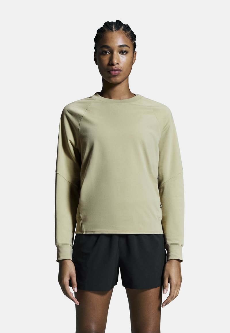 Beige lang mouwtop met een ronde halslijn, raglanmouwen, en geribbelde manchetten, gecombineerd met zwarte short. Gladde, lichte stof.