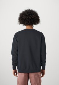 Mörk marinblå crewneck sweatshirt med långa ärmar. Ribbad mudd och nederkant. Slät textur, som visar en enkel, odekorerad design.
