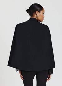 Mantello nero con un design strutturato, caratterizzato da un ampio collo e una silhouette fluente. Texture liscia con linee pulite e senza hardware visibili.