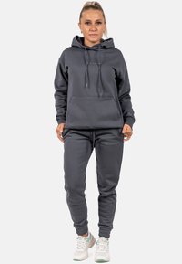 Felpa con cappuccio grigia scura, dotata di tasca frontale, cordini regolabili e pantaloni coordinati, caratterizzati da polsini elasticizzati e un branding discreto.