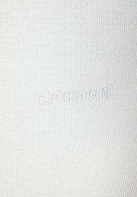 Bijela rebrasta tkanina sa suptilnom teksturom sadrži izvezeni natpis "CPNHGN" u odgovarajućoj boji. Nema dodatnih ukrasa ili uzoraka.