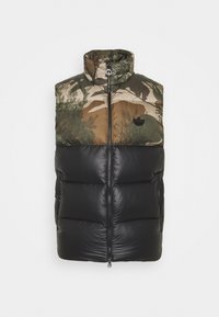 Kamizelka z wyściółką, z górną częścią w kamuflażu w ziemistych odcieniach i dolną częścią w czarnym, błyszczącym wykończeniu. Posiada stójkę oraz zamek błyskawiczny z przodu.