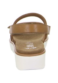 Braune Ledersandale mit verstellbarem Riemen, strukturiertem Fußbett, weißer Plateausohle und Markierung auf der Innensohle.