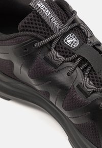 Black athletic shoe with mesh upper, textured overlays, and rubber sole. Features logo tag and patterned laces for added detail.