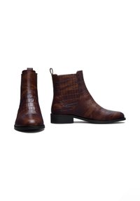 Braune Leder-Stiefeletten mit Kroko-Optik, ausgestattet mit einem niedrigen Absatz und seitlichen elastischen Einsätzen für ein einfaches Hineinschlüpfen.