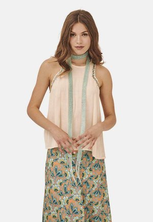 Top sin mangas de color rosa claro con detalles de cuentas y un cuello atado, combinado con una falda de patrón floral en tonos naranjas y verdes.
