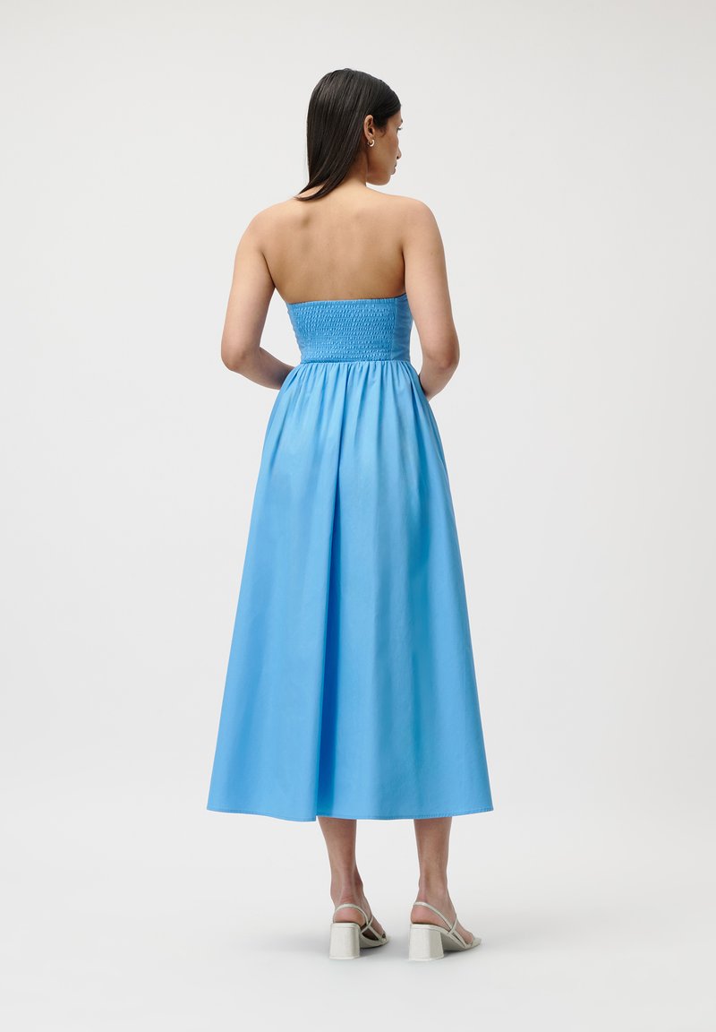 Niebieska, bezramiankowa sukienka maxi z marszczonym stanikiem i zwiewnym dołem. Gładki, lekki materiał o długości do połowy łydki.
