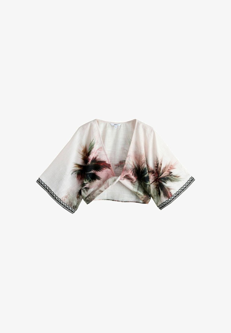Blouse courte beige clair à enfiler avec manches larges, imprimé de palmiers et bordure décorative noire sur les bords des manches.